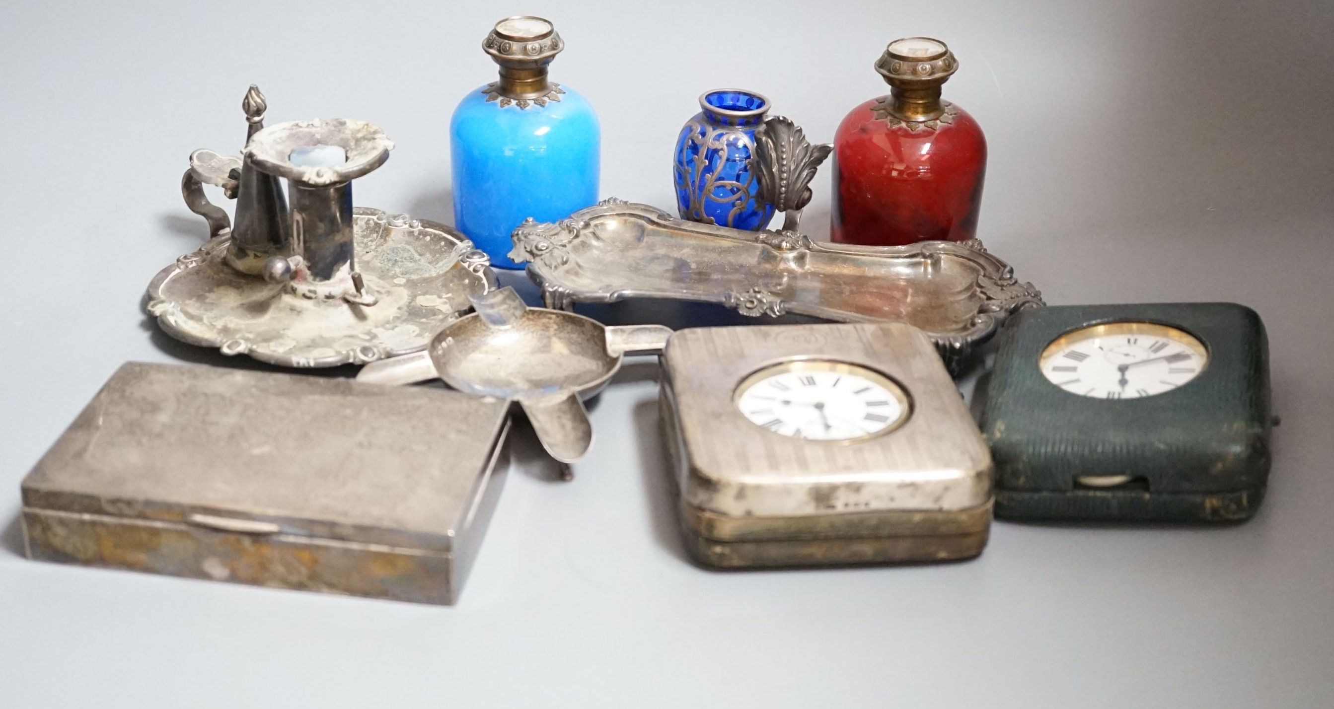 An Edwardian silver mounted travelling pocket watch case with 8-day pocket watch, one other travelling pocket watch in case, a silver mounted cigarette box, a silver ashtray, a plated snuffers stand and plated chambersti